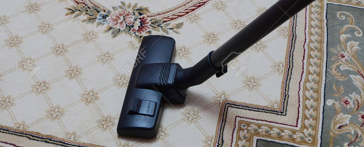 Vacuuming a patterned rug before deep cleaning